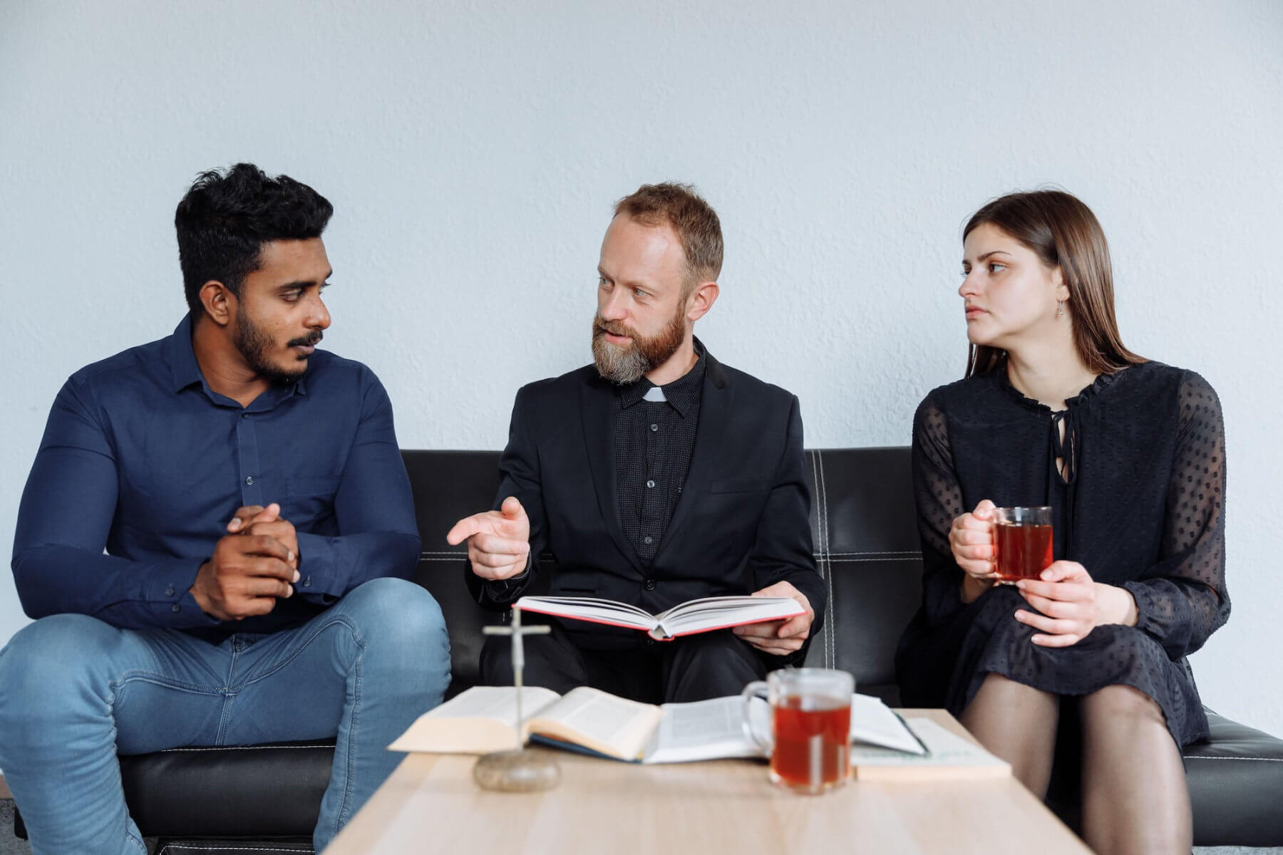 Pastor holding a Bible while counseling a couple during a faith-based counseling conversation